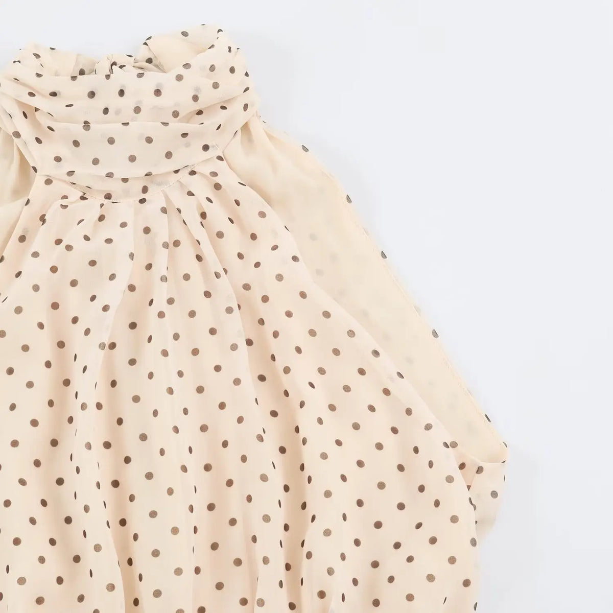 Macro detail of sheer beige chiffon fabric with brown polka dot print