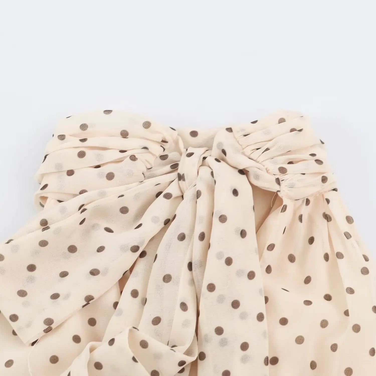 Macro close‑up of fabric bow knot at back halter neck of beige maxi dress