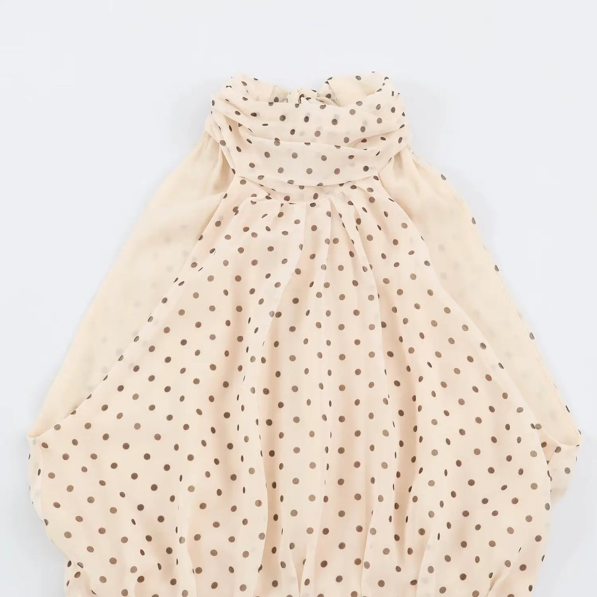 Close‑up of draped halter neckline on beige polka dot maxi dress