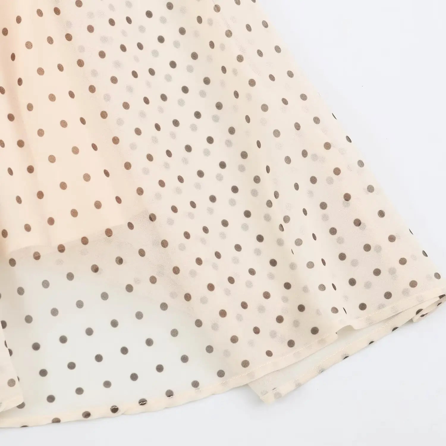Close‑up of hem stitching on beige chiffon maxi dress with brown polka dots