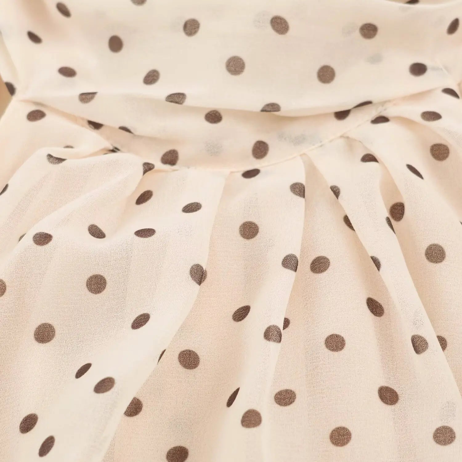 Partial view of flowy pleated skirt and soft fabric drape on beige maxi dress