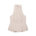 Flat lay view of a beige halter peplum top with red polka dots, featuring a back tie closure and flared peplum hem.