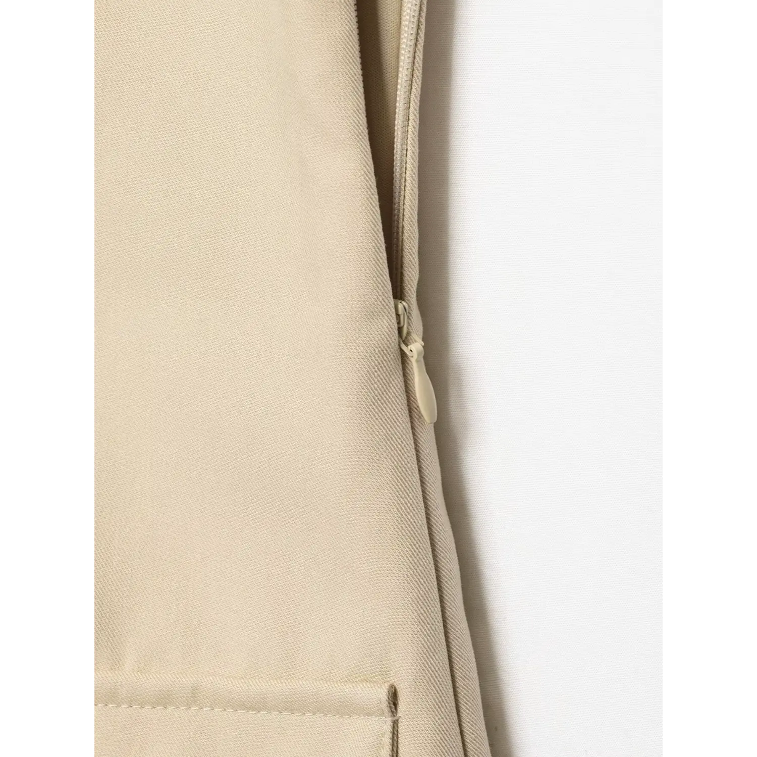 Close‑up of side invisible zipper on beige sleeveless trench mini dress