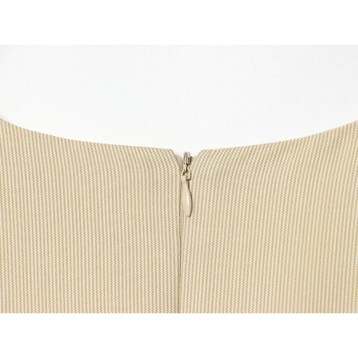 Close-up of the back zipper pull on the beige fine-striped dress