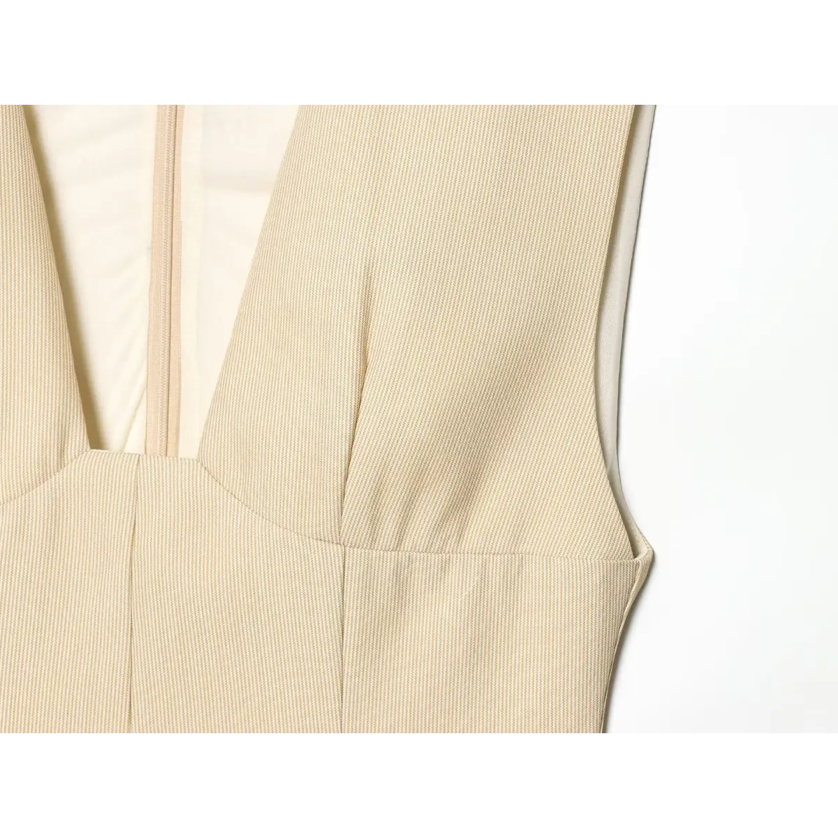 Front bodice detail of the beige fine-striped dress, highlighting the V-shaped neckline and tailored bust

