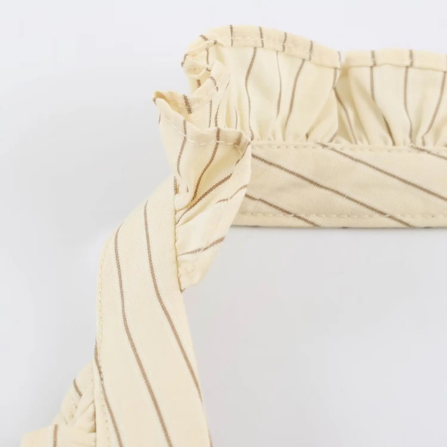 Close-up of ruffled halter neck on beige vertical striped mini dress
