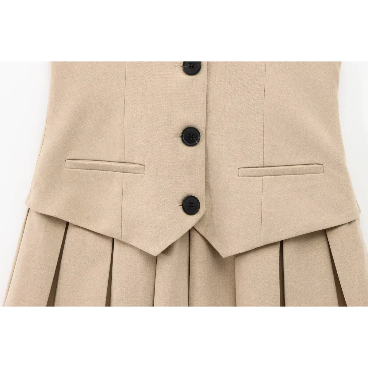 Full front view of the beige tailored vest-style pleated mini dress, displaying the three-button placket and symmetrical pockets.