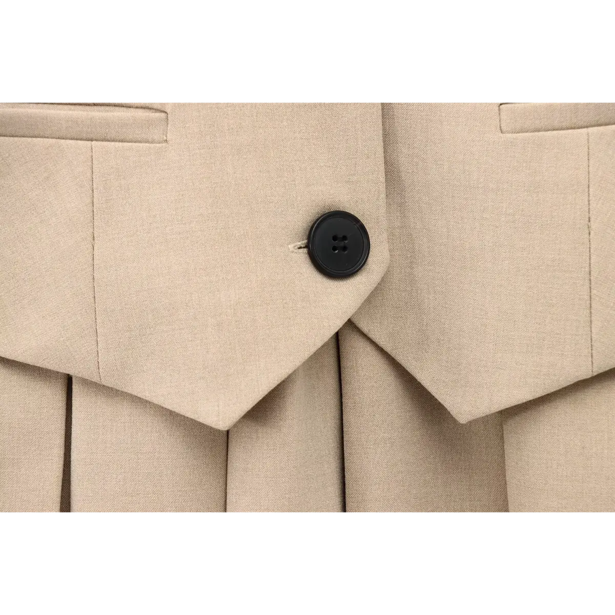  Close-up of the waist seam where the vest-style top meets the pleated skirt, emphasizing the structured silhouette.