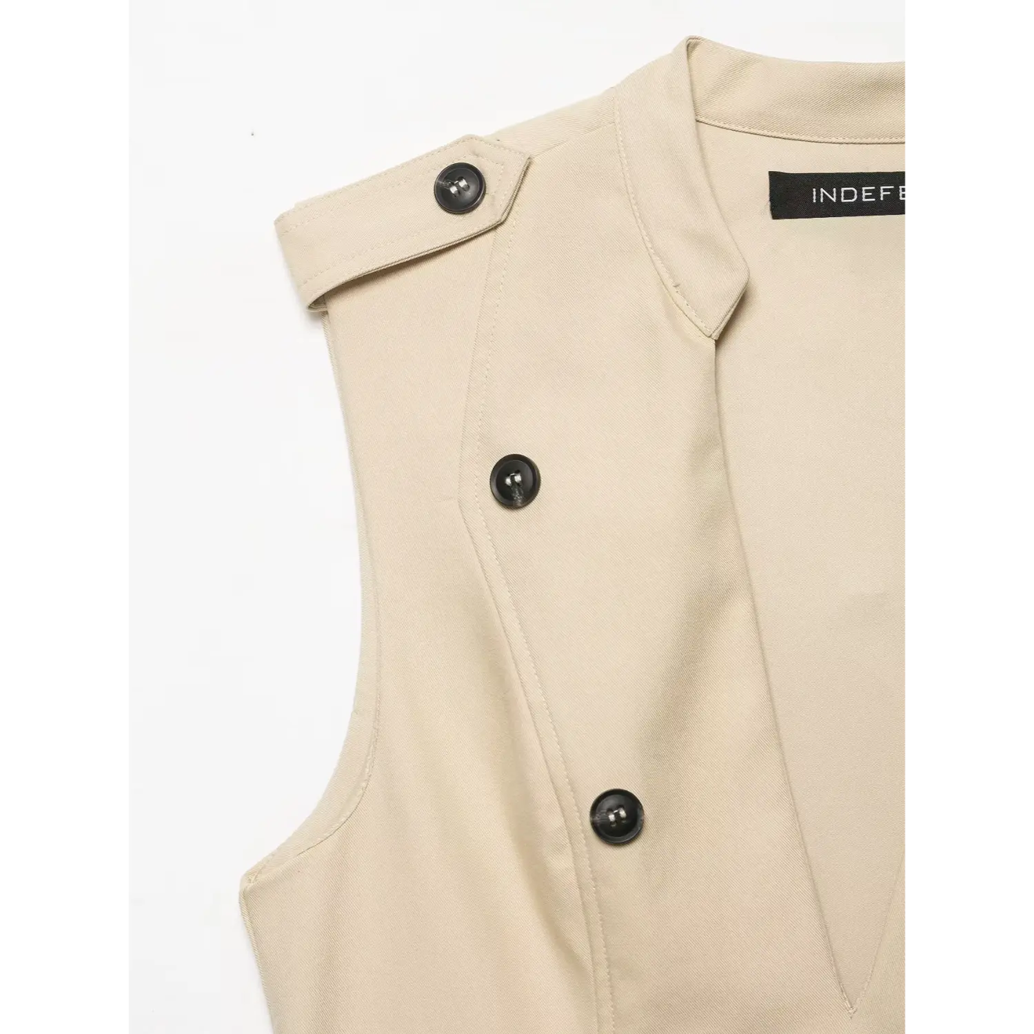 Close‑up of shoulder epaulet and black button detail on beige sleeveless trench mini dress