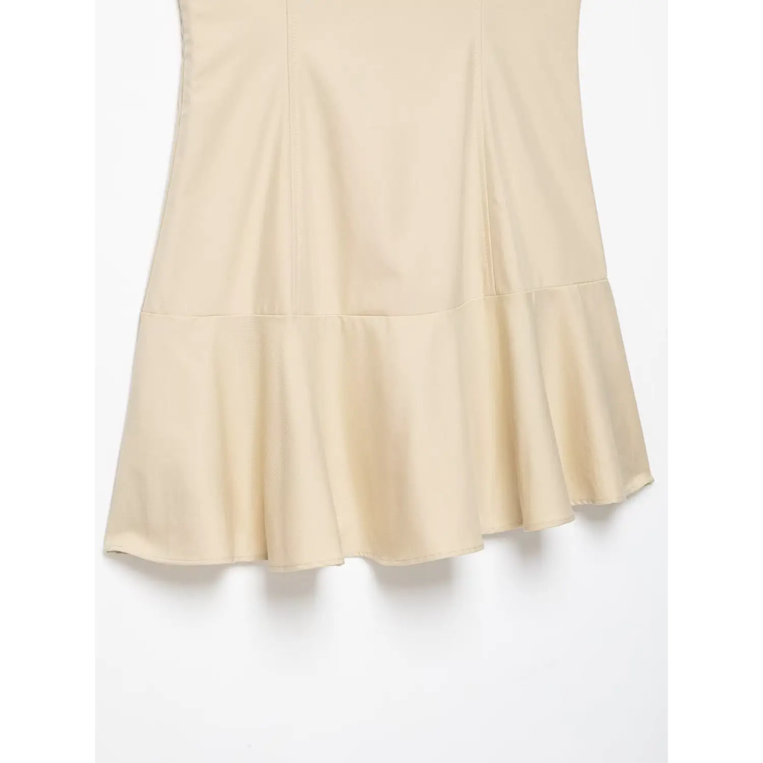Close‑up of flared ruffle hem, seam construction of beige sleeveless trench mini dress
