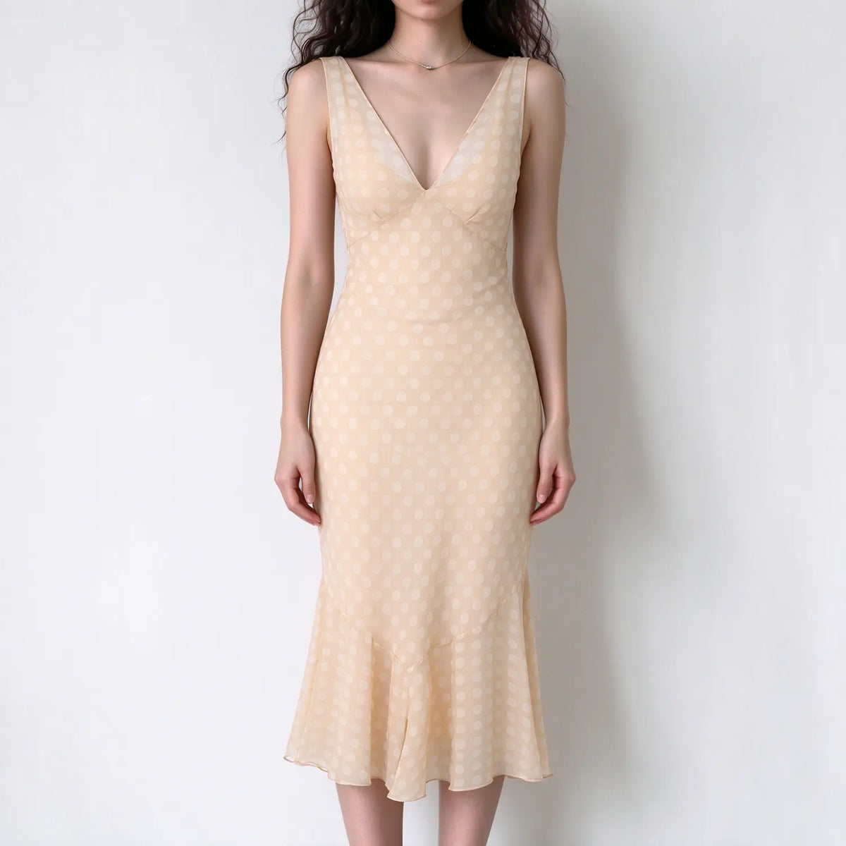Model wearing beige white polka dot sleeveless v-neck midi dress with mermaid flared hem, white background