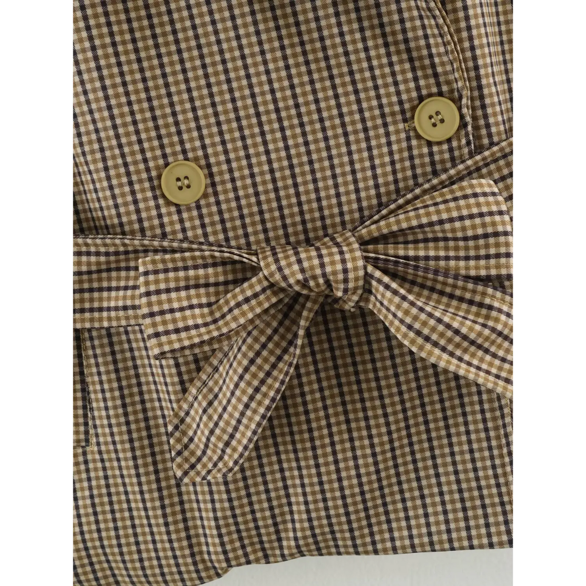 Close-up of gingham self belt bow and buttons