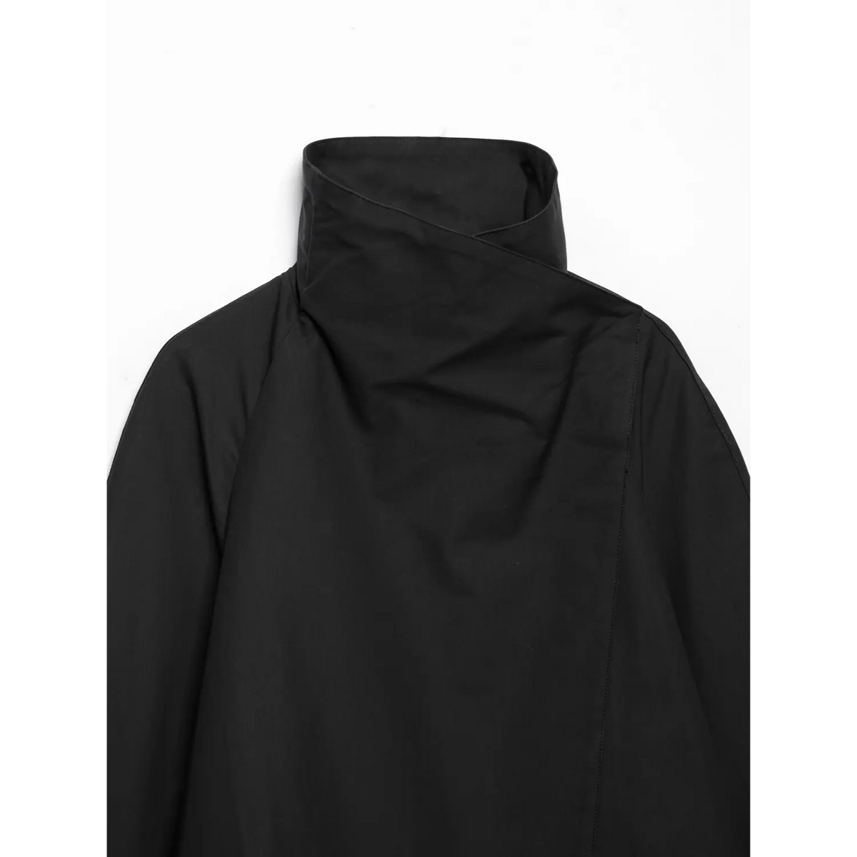 Close-up shot of black cropped jacket, draped asymmetric wrap high collar and raglan shoulder seam