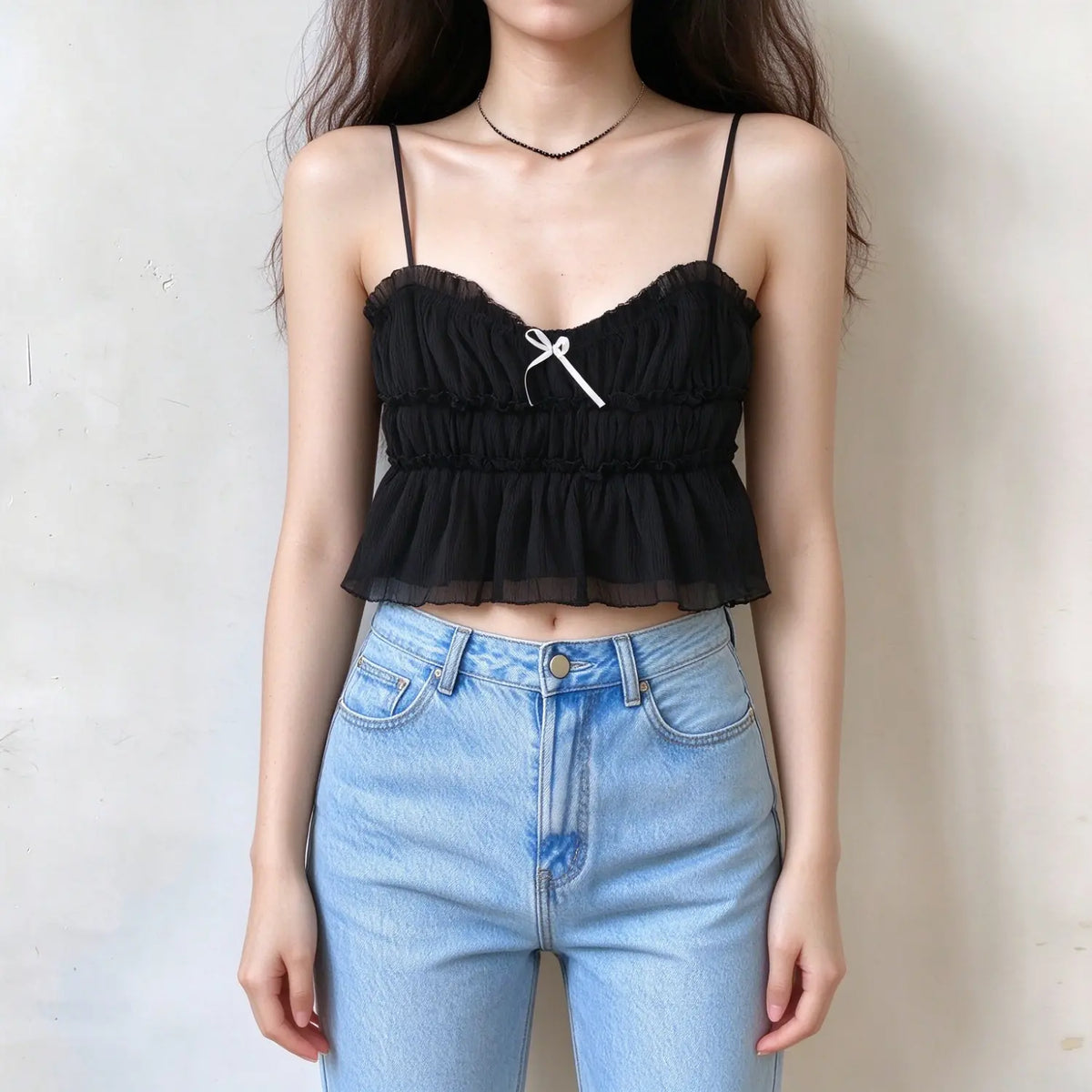 Model wearing black bow smocked ruffle cami top with jeans, front view