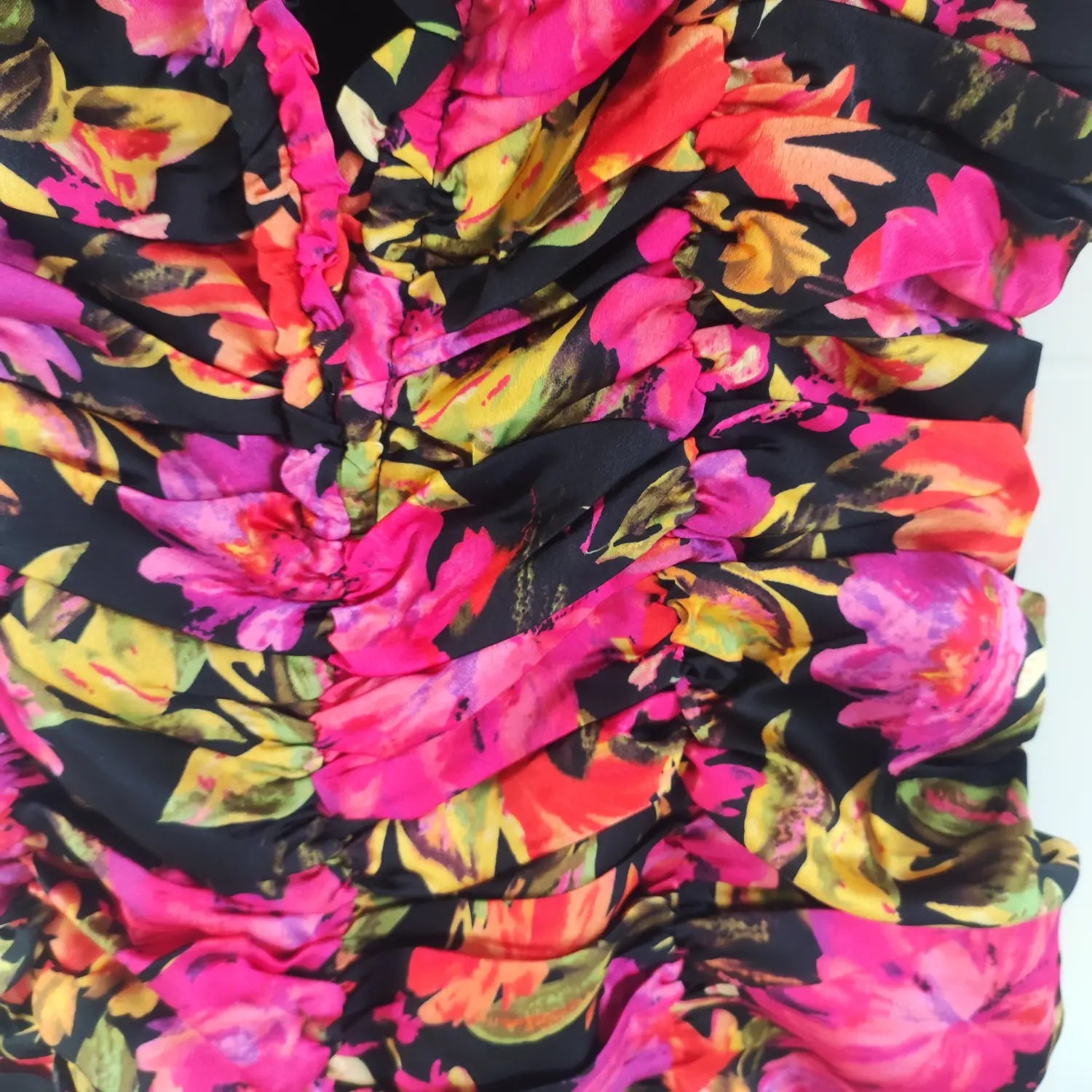 Extreme close‑up front bodice ruched fabric texture black base vibrant pink orange floral print mini dress
