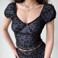 Close up black sheer mesh crop top with allover flock butterfly print, sweetheart v neck, tiny front satin bow, puff short sleeve scallop lace trim