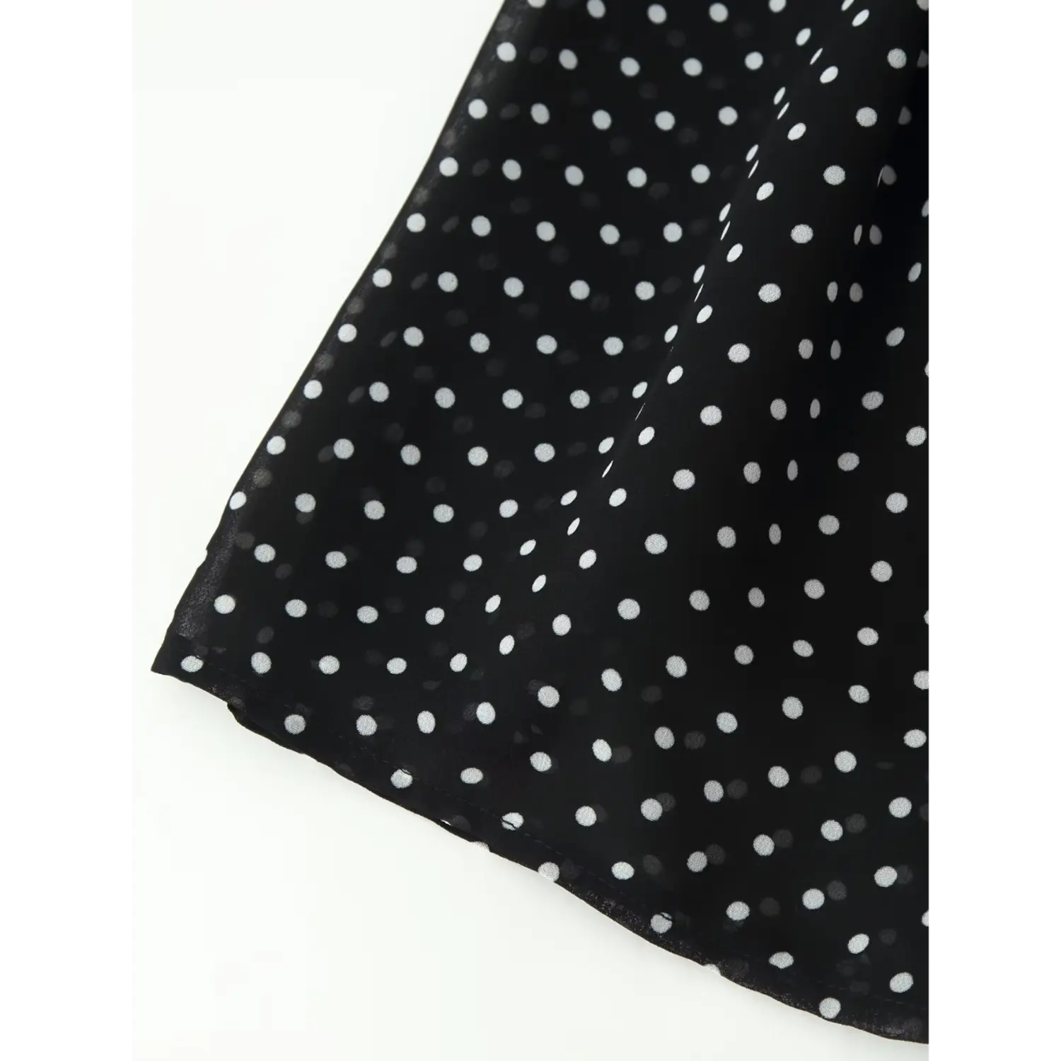 Closeup shot, black chiffon polka dot dress with stitched hem edge and flared skirt detail