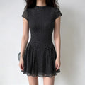 Model lifestyle shot, black chiffon fitted mini dress with stand collar, cap sleeves and polka dot print