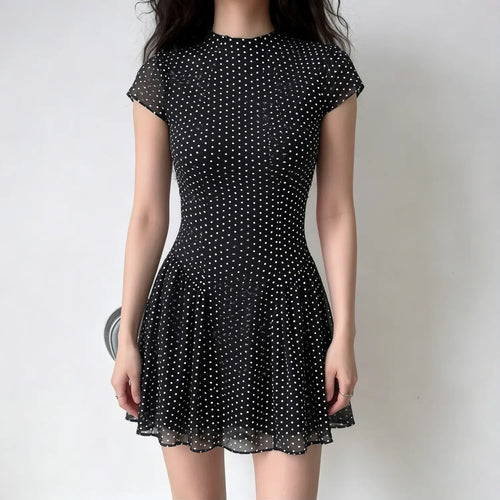 Model lifestyle shot, black chiffon fitted mini dress with stand collar, cap sleeves and polka dot print