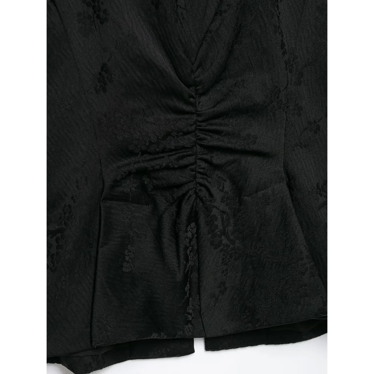 Close‑up detail of back waist ruched gathering on black jacquard new chinese jacket, dark floral woven texture