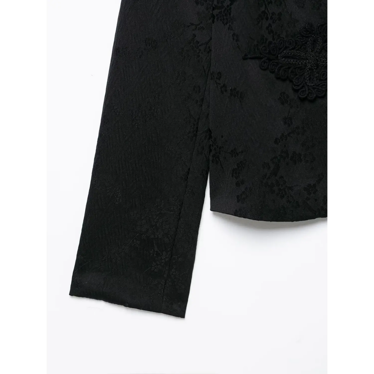 Close‑up shot of black chinese style jacket long sleeve and hem, dark floral jacquard woven texture