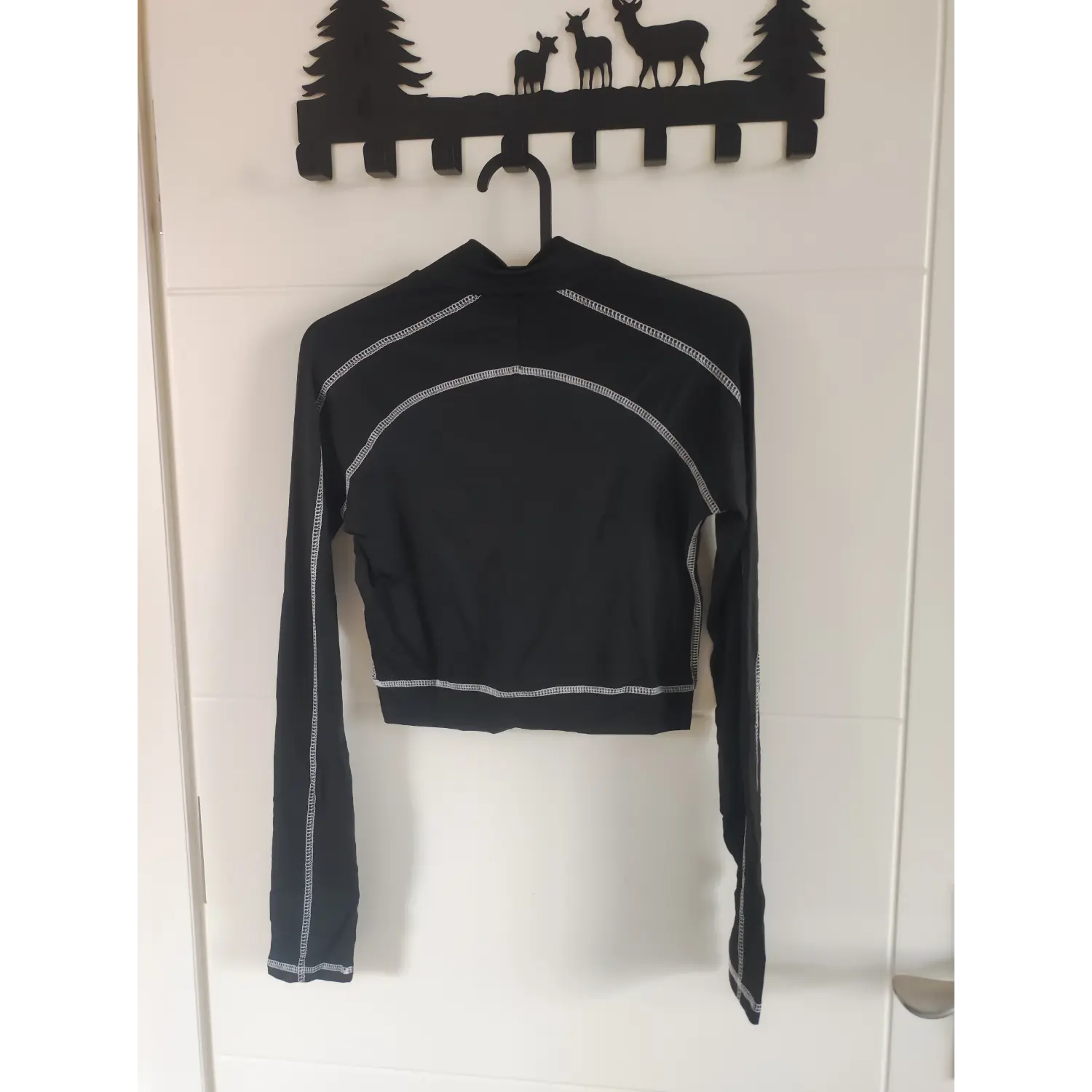 Hanging back view black stand collar long sleeve cropped top with white contrast stitching seams