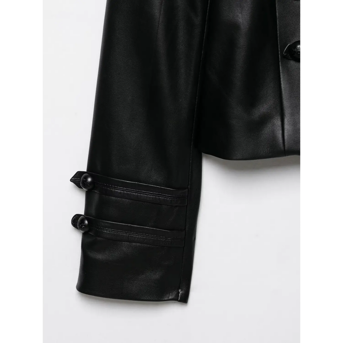 Cuff closeup of black cropped leather jacket, decorated double button strap on sleeve