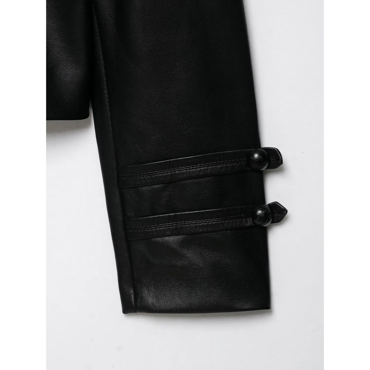 Macro close-up of sleeve decorative buttons on black cropped leather jacket