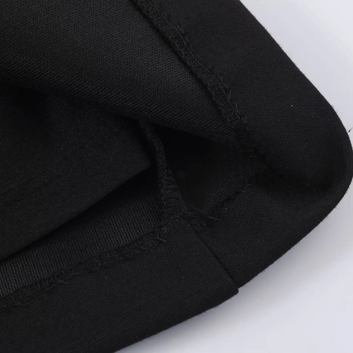 Close-up of finished overlock stitching along the dress hem, black fabric