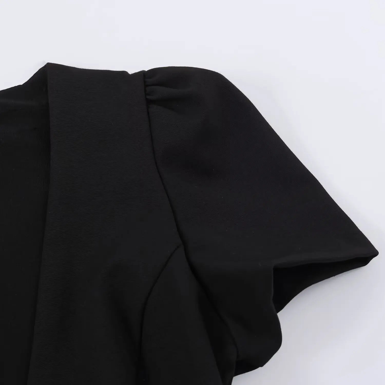Close-up shoulder view showing gathered puff short sleeve of black V-neck dress