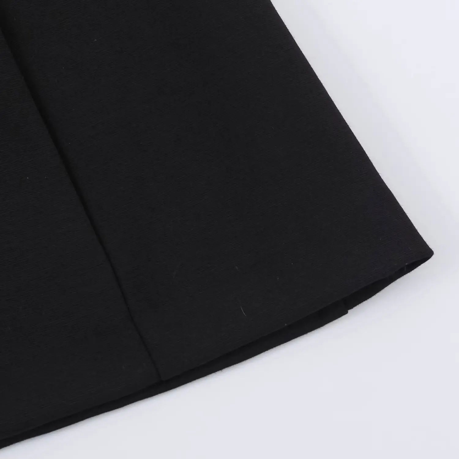 Close-up view of straight mini skirt hem and vertical shaping seams of black dress