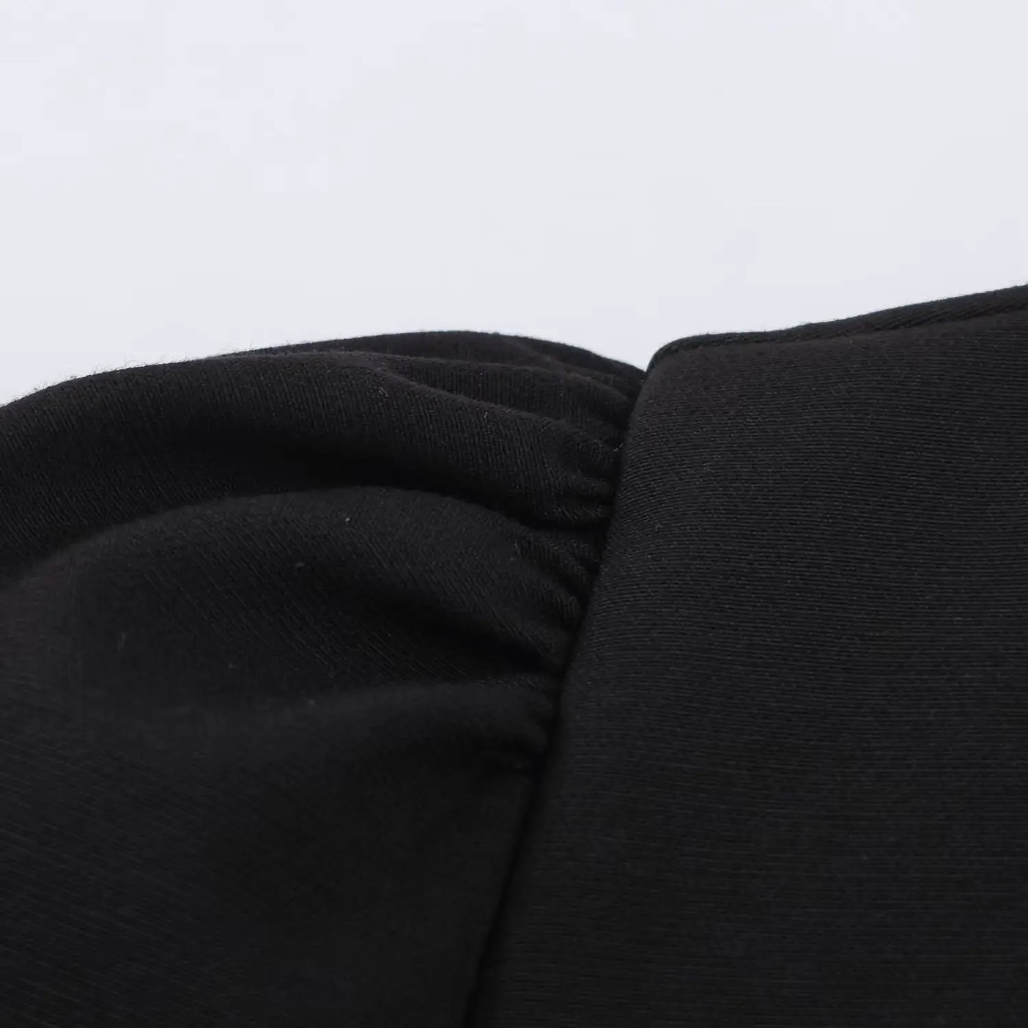 Macro close-up of gathering stitching on puff sleeve shoulder seam, black fabric