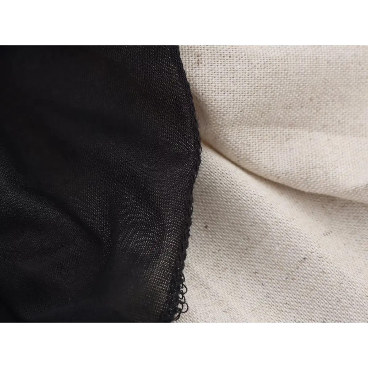 Close-up shot of the fabric textures on a black faux-leather mini dress, showing the smooth leather and woven beige skirt material.