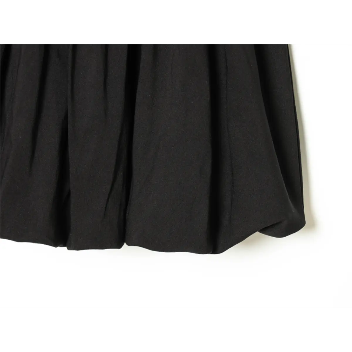 Hem detail of black fit-and-flare dress, showing the flared skirt and gathered fabric texture