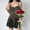 Front lifestyle shot on model of black floral lace slip mini dress, thin spaghetti straps, sweetheart neckline, semi sheer mesh fabric, ruffle hem vintage dress