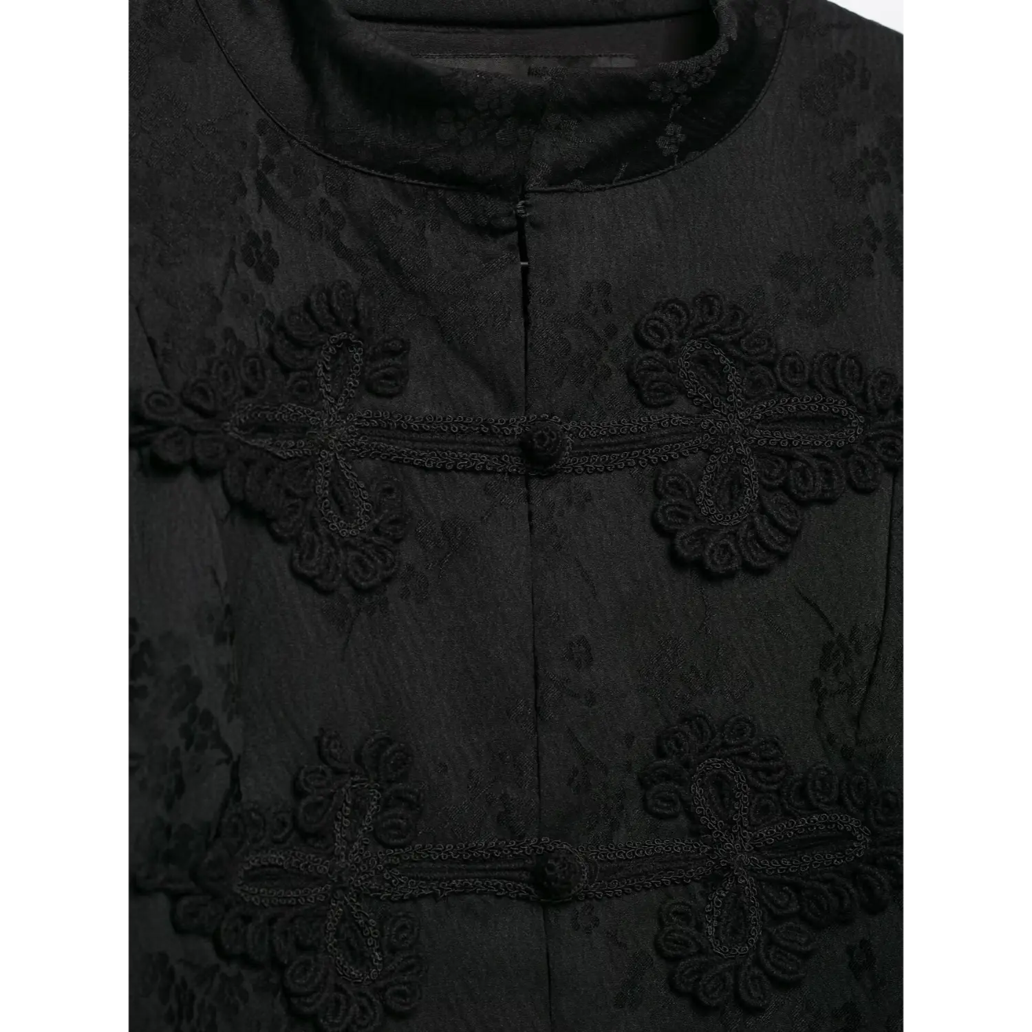 Macro close‑up of chinese frog knot embroidery on black mandarin collar jacket, jacquard woven floral fabric