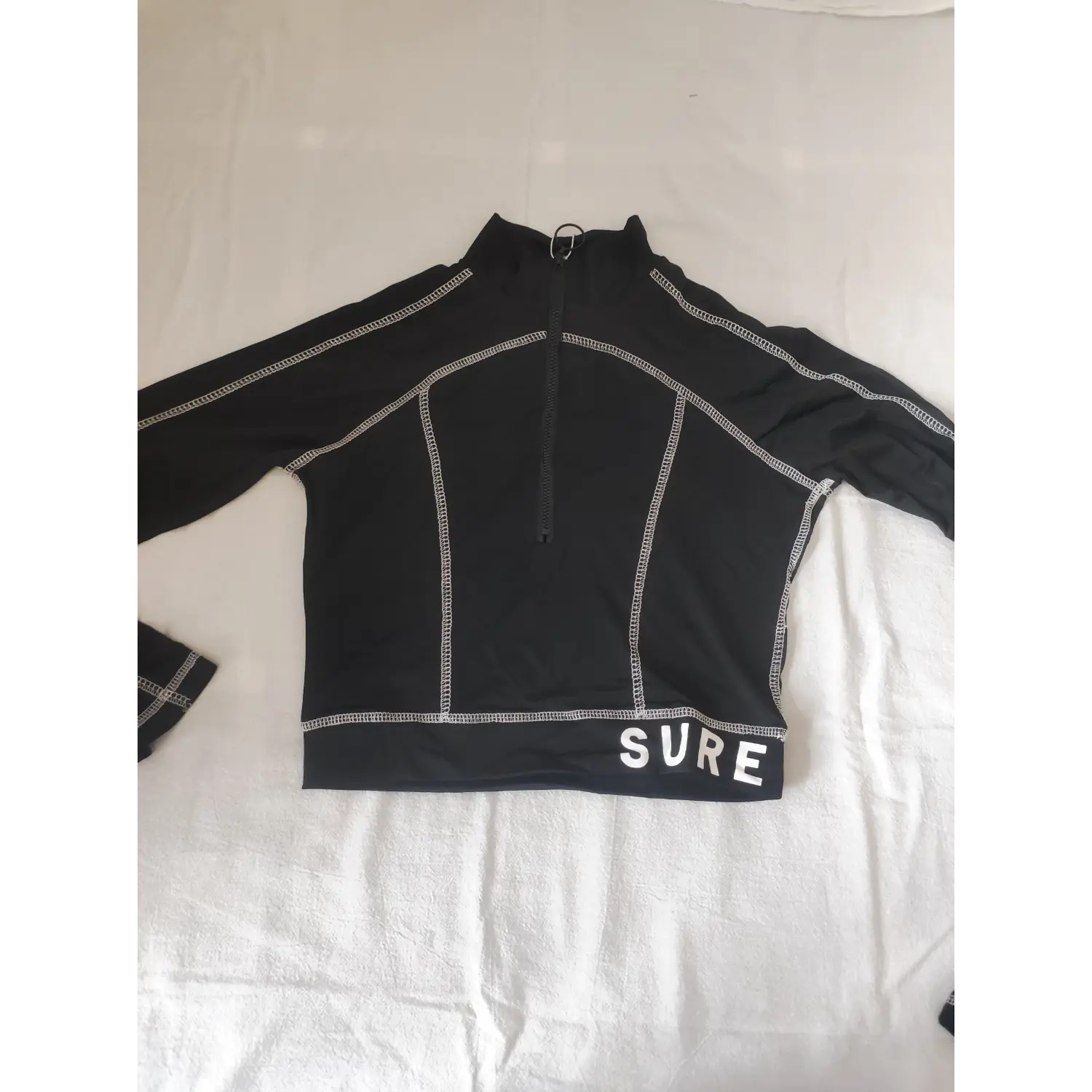 Flat lay front black stand collar half zip long sleeve cropped top with white SURE letter print hem