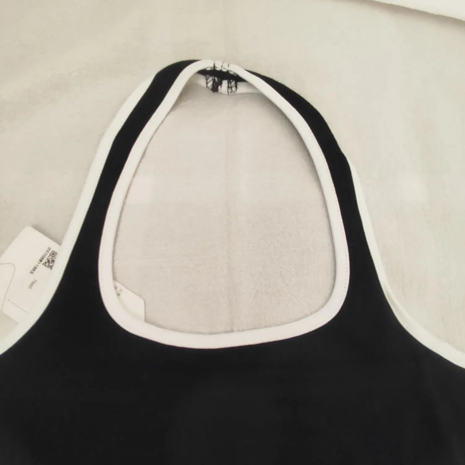 Close‑up halter neck back zipper and white piping trim detail of black bodycon dress