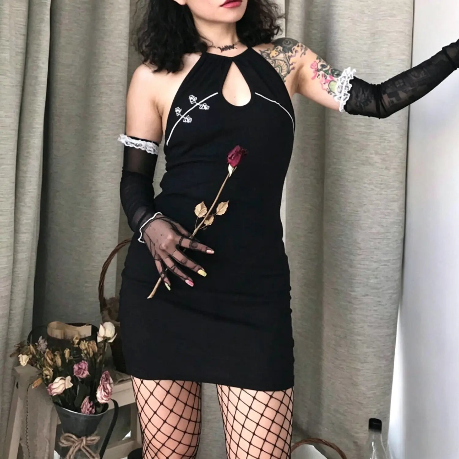 Full front model pose wearing black halter keyhole mini dress with white floral embroidery