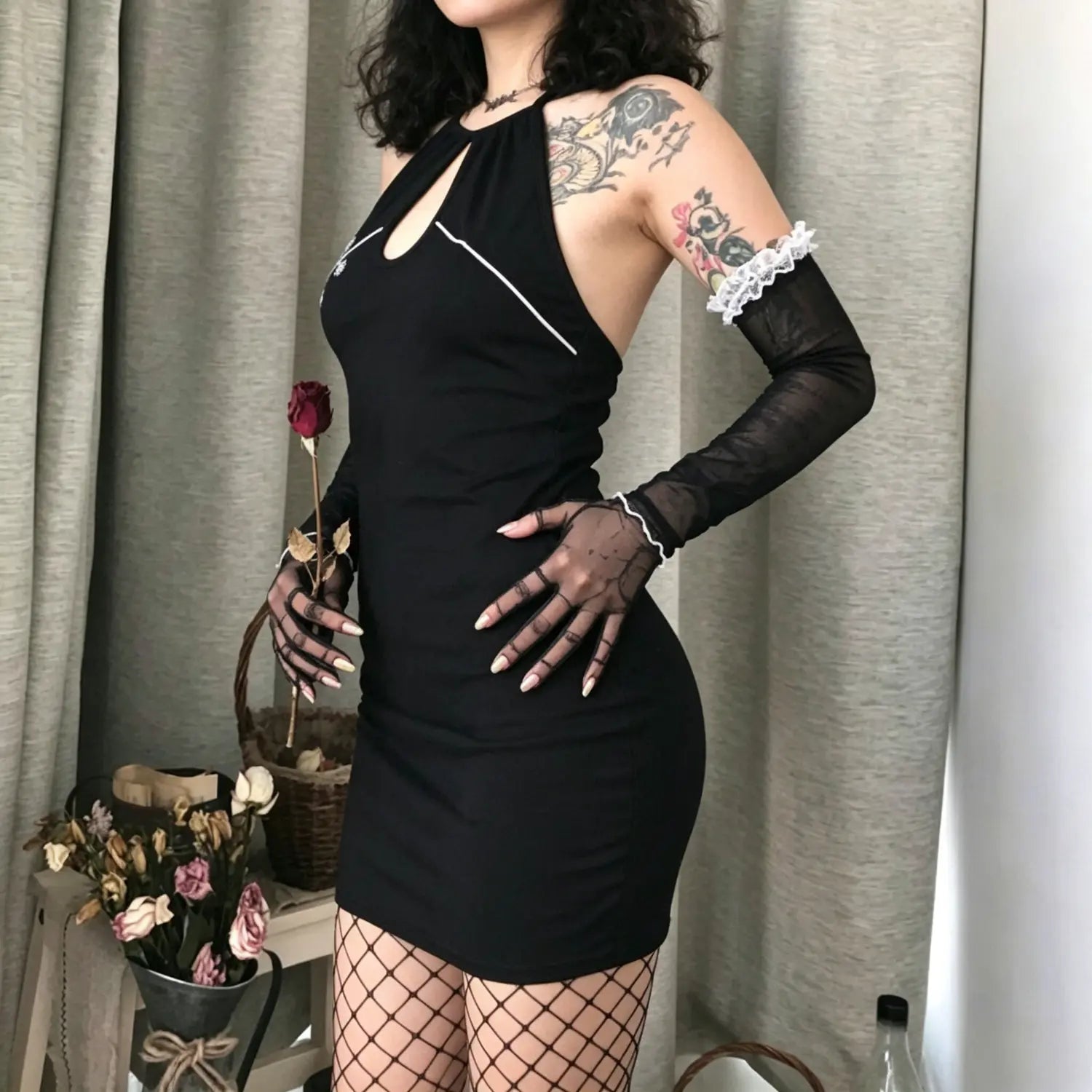 Side view model shot of black ribbed halter keyhole neck mini dress with white floral embroidery
