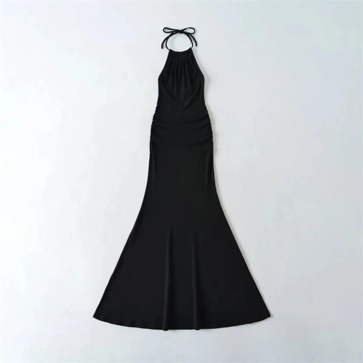  Flat lay view of a black halter-neck mermaid maxi dress, showing the full form-fitting silhouette and tied halter straps.