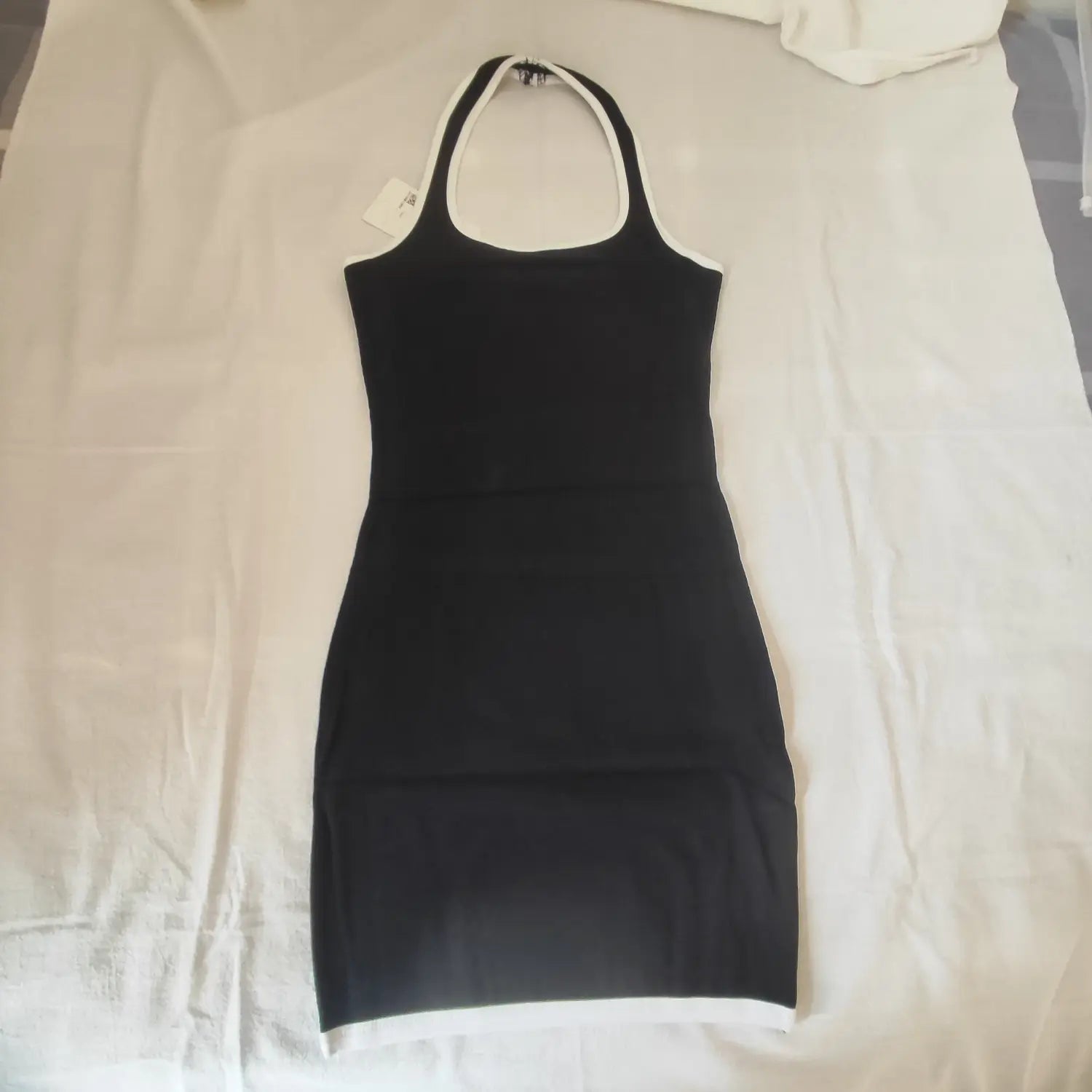 Flat lay front view black halter neck ribbed bodycon mini dress with white trim