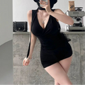  A woman wearing a black ribbed halter wrap top with a tie detail, styled with black shorts and a hat, taking a mirror selfie.