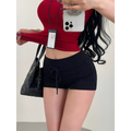 Close-up of a woman wearing black high-waisted drawstring shorts with a red cropped top, styled with a quilted bag.
