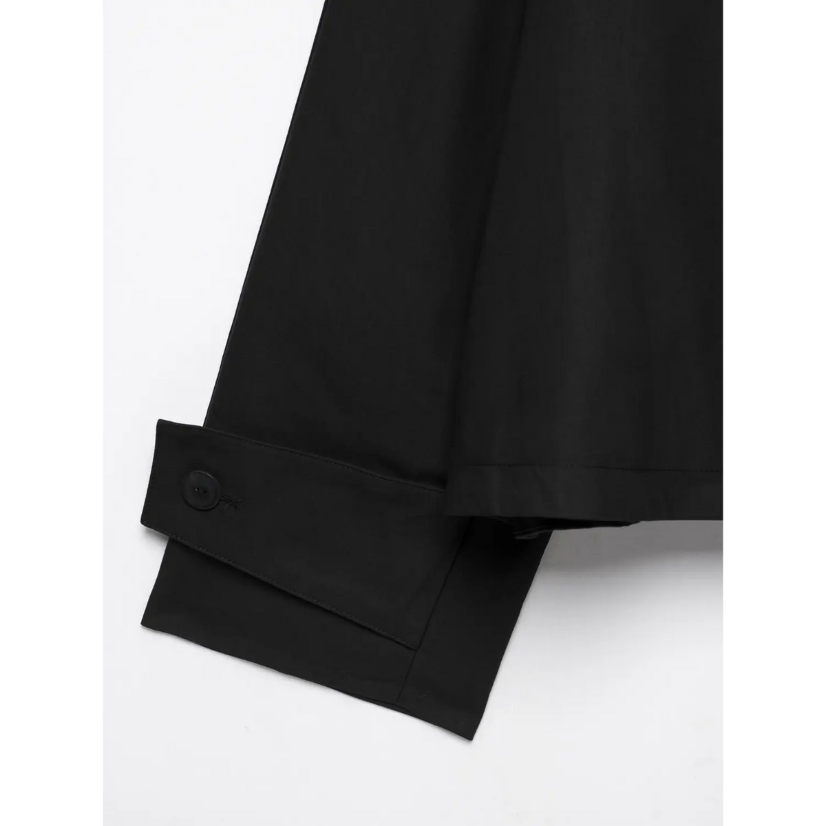 Macro shot of black jacket sleeve cuff, single black button and folded cuff design