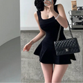 A woman wearing a black knit mini dress with a square neckline, textured pattern, and flared skirt, styled with a black quilted bag.