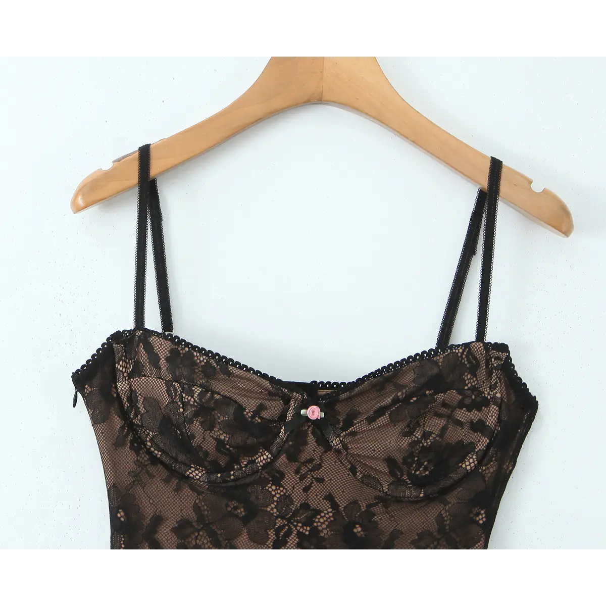 Partial view on wooden hanger showing the double spaghetti straps and lace-trimmed neckline