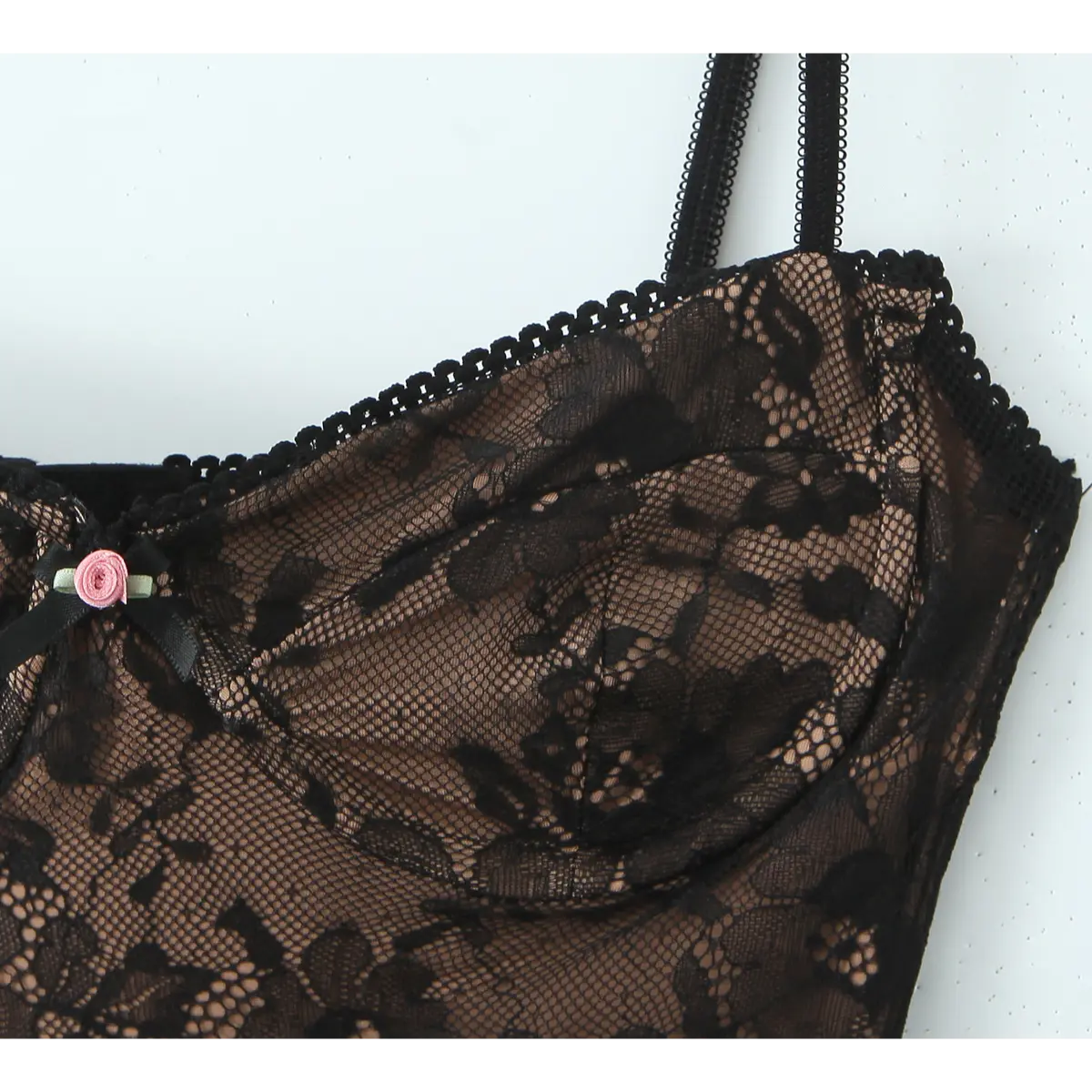 Close-up of the underwired floral lace bust cup with a tiny pink rose and bow accent on the black slip dress