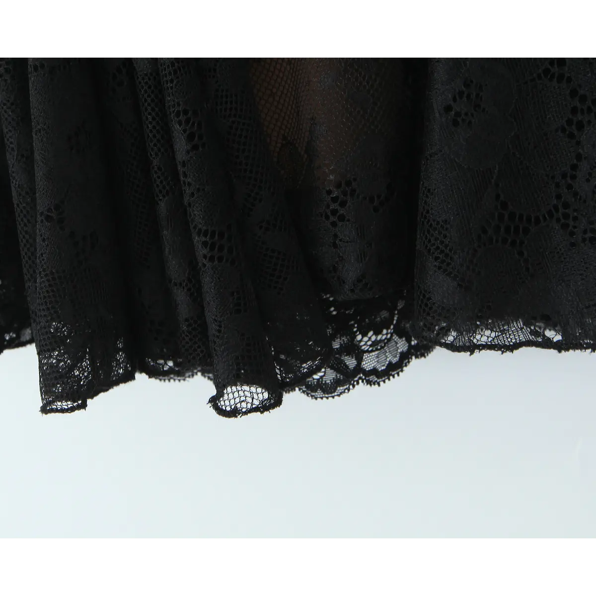 Close-up of the scalloped lace hemline on the flared skirt of the black slip dress
