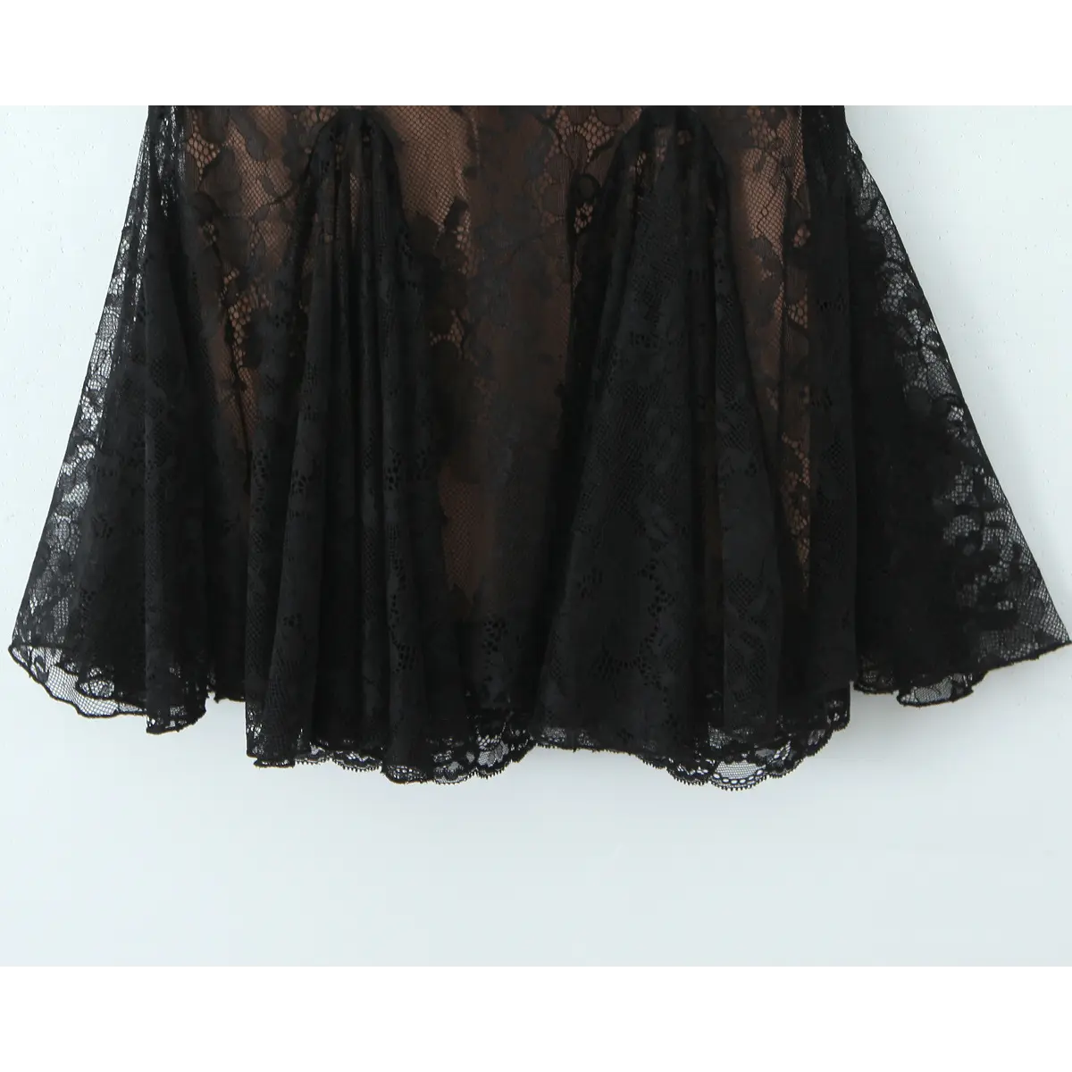 Close-up of the flared babydoll skirt with layered black floral lace and scalloped hem